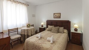 A hotel room with a bed, two bedside tables, a chair, a small table, and a window with curtains. - Comtessa in Oliva With 1 Bedrooms and 1 Bathrooms (Oliva)