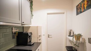 Kompakti keittiö, jossa on sisäänrakennettu liesi, kahvinkeitin ja roskakori.
