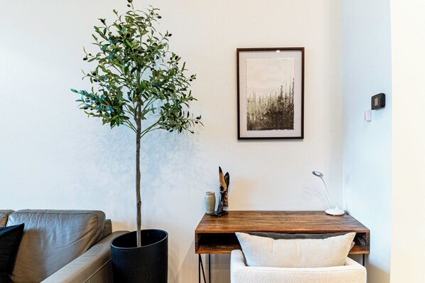 A living room with a wooden table, a potted plant, a framed picture on the wall, and a modern lamp. - Retro Vibe, downtown Grand Forks (Grand Forks)