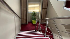 A staircase with a red carpet, metal railings, and wooden paneling on the walls. - RESIDENCE SYCOMORE 1 (Abidjan)