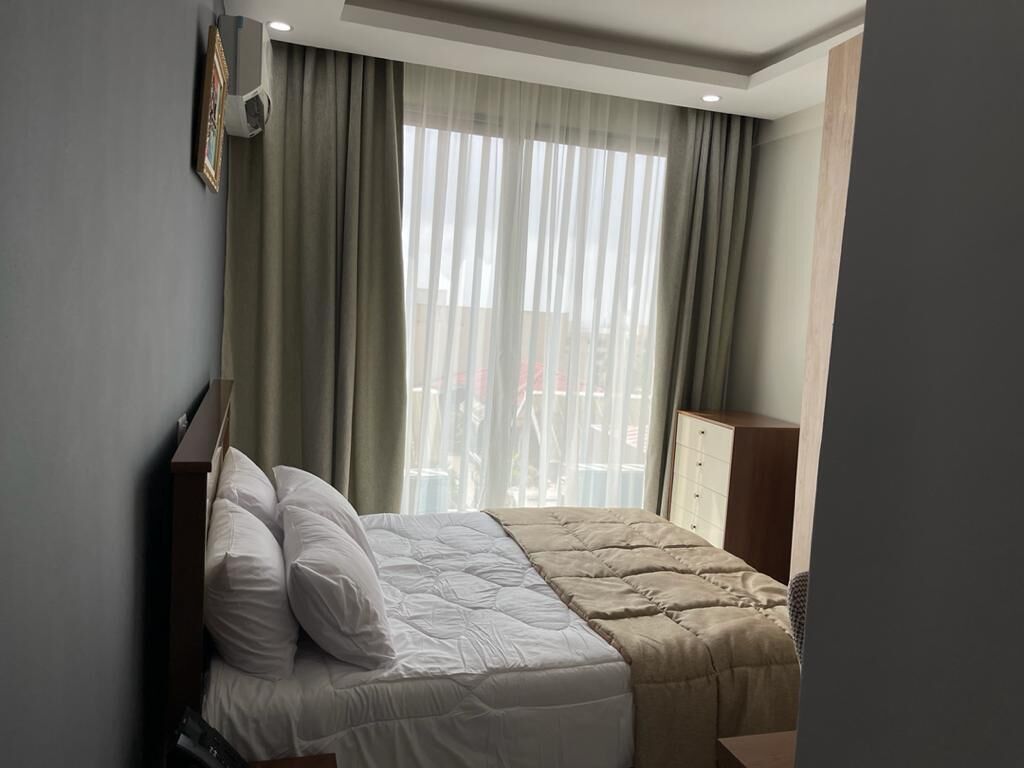 Une chambre d’hôtel avec un lit, des rideaux, une armoire et une fenêtre donnant sur un paysage agréable.