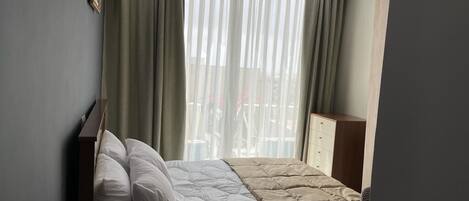 Habitación de hotel con cama, cortinas, armario y ventana con vistas.