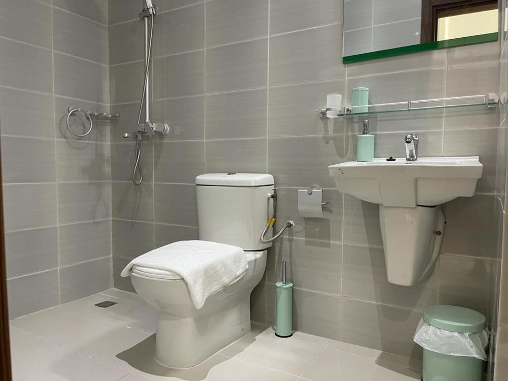 Casa de banho com sanita, chuveiro e lavatório.