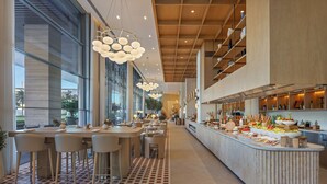 Un restaurante moderno con una barra alargada, varias zonas de estar y diversas exhibiciones de comida y bebidas.