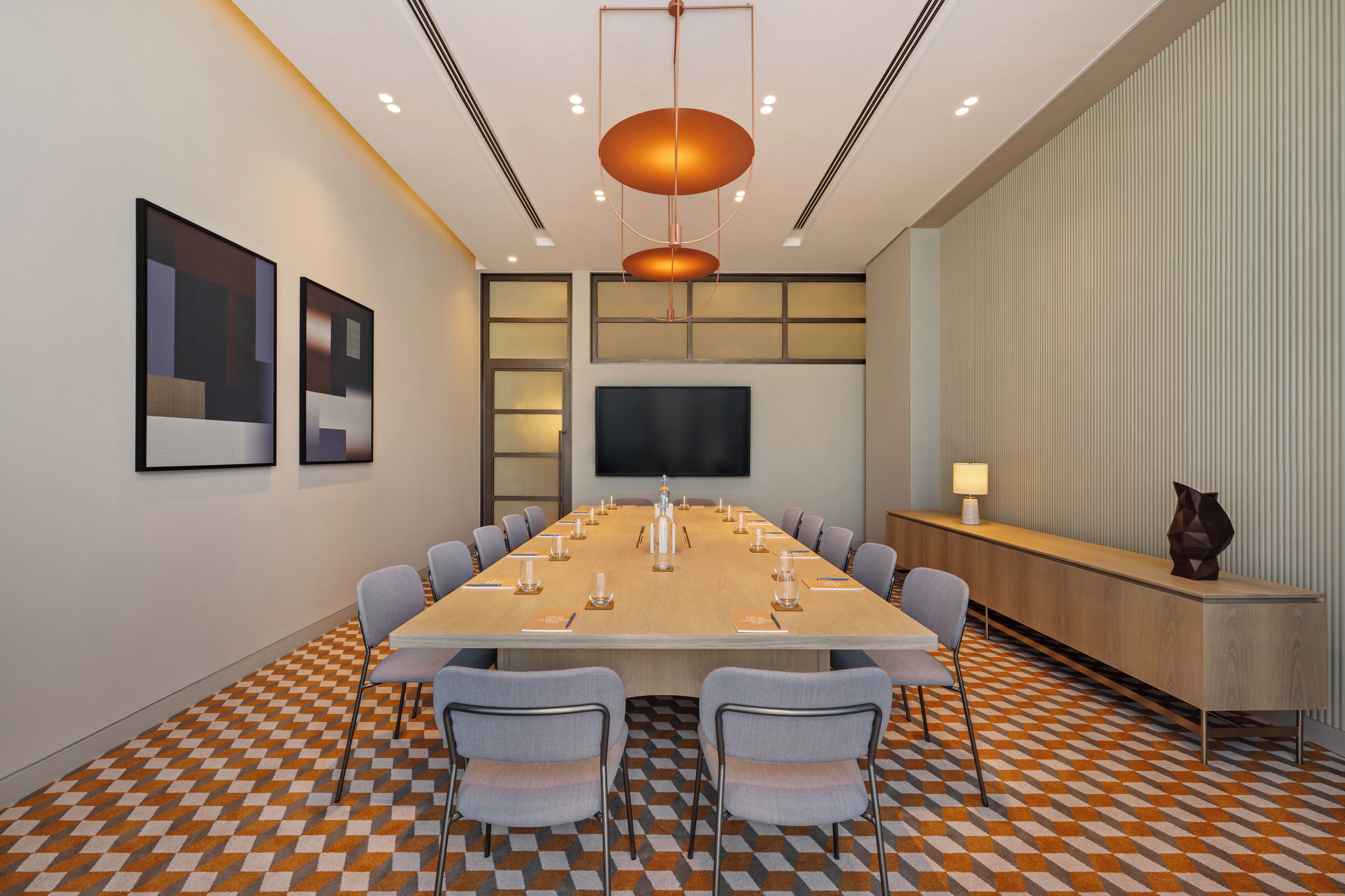 A conference room with a long table, chairs, a TV, and a patterned floor.