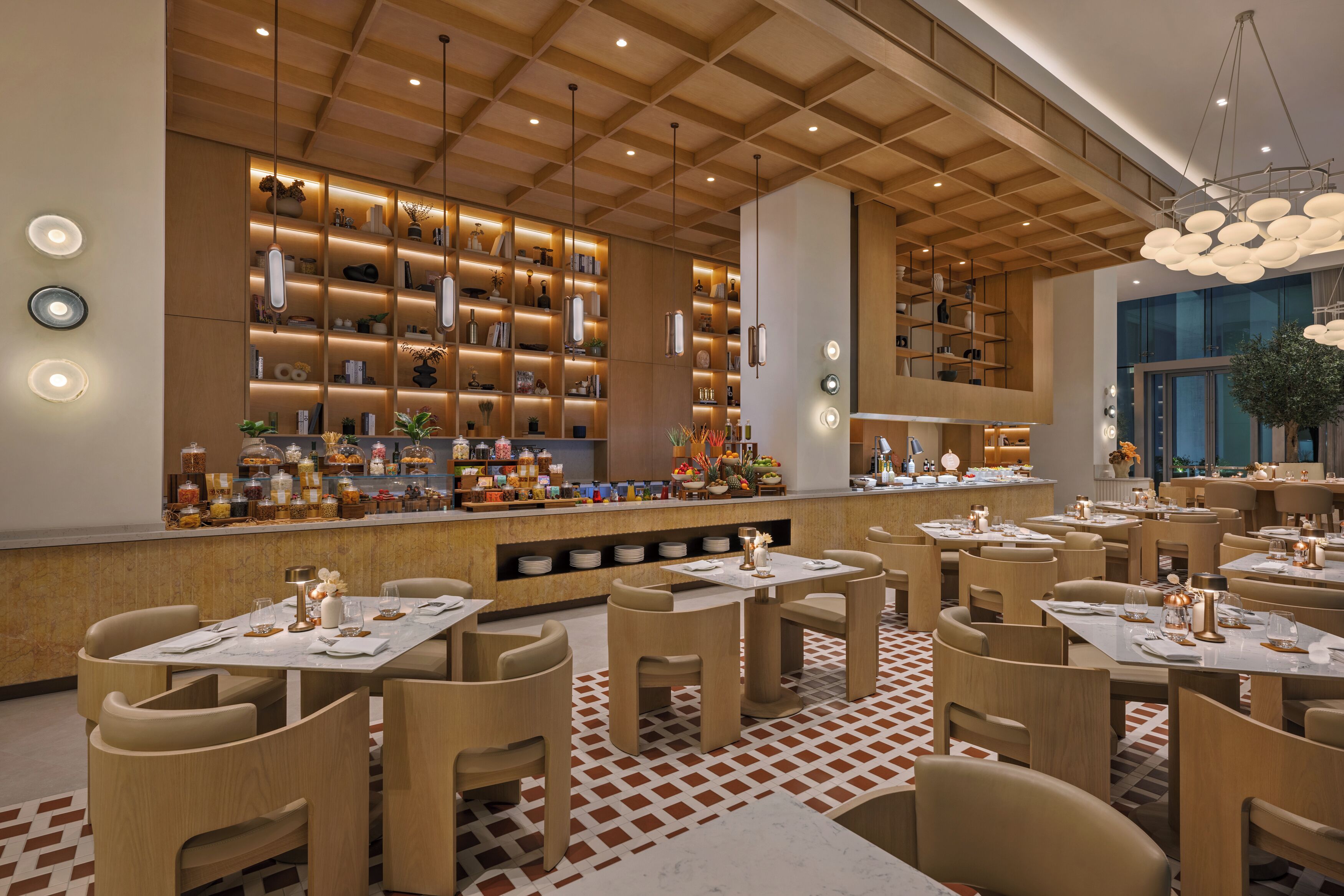 A modern restaurant interior with wooden panel ceilings, a central bar area with shelves of bottles and glassware, and multiple dining tables with chairs.