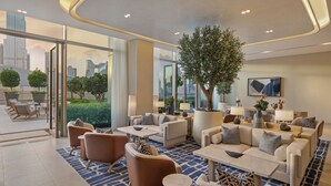Un moderno vestíbulo de hotel con un gran árbol, asientos cómodos y vistas de la ciudad.