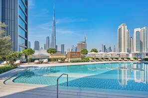 A swimming pool with lounge chairs and umbrellas, surrounded by modern buildings and a clear sky. - Vida Dubai Mall (Dubai)