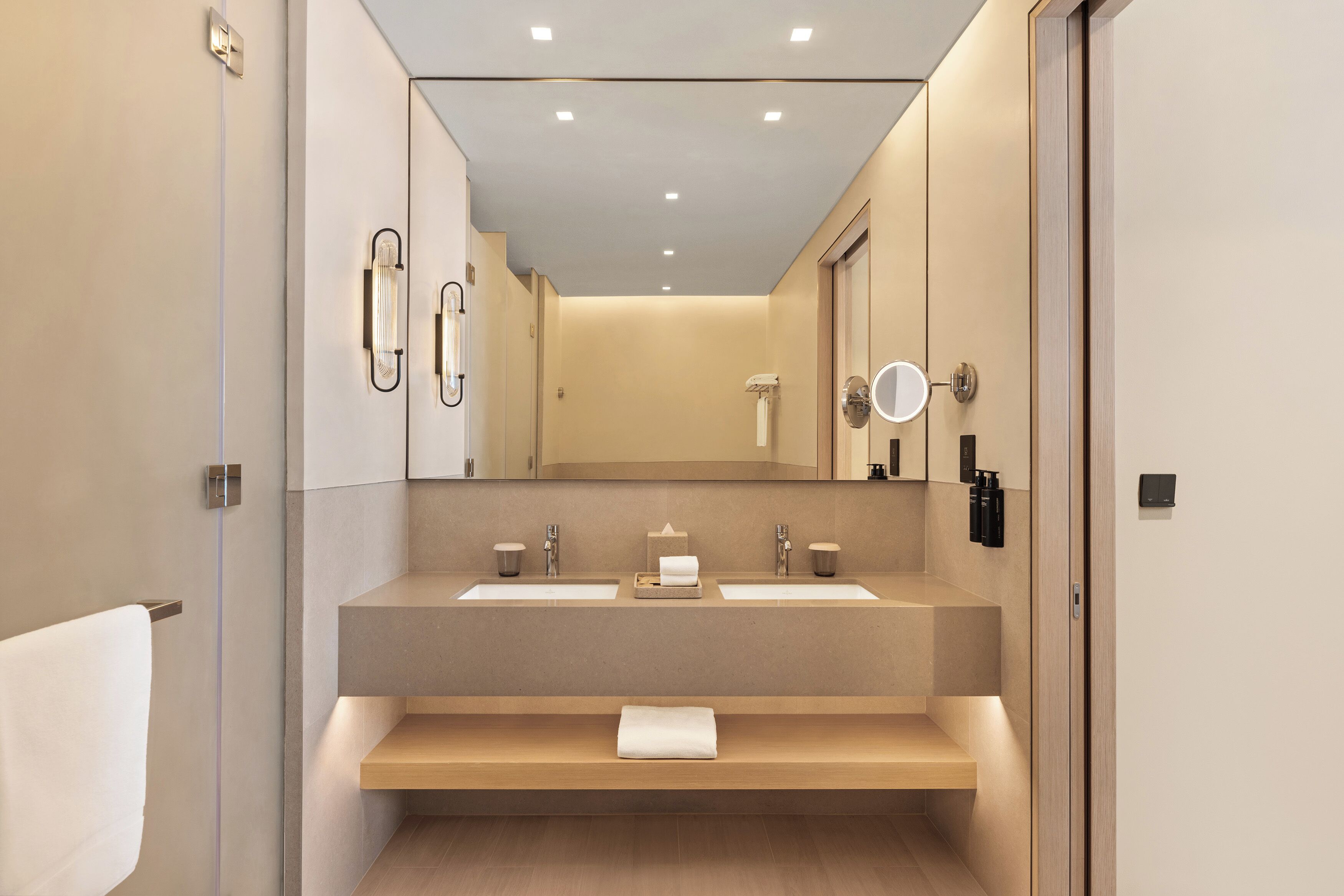 A modern bathroom with two sinks, a mirror, and a towel rack.