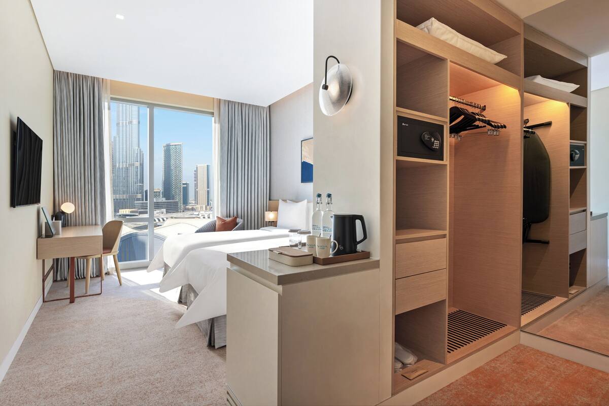 A hotel room with a bed, desk, and closet.