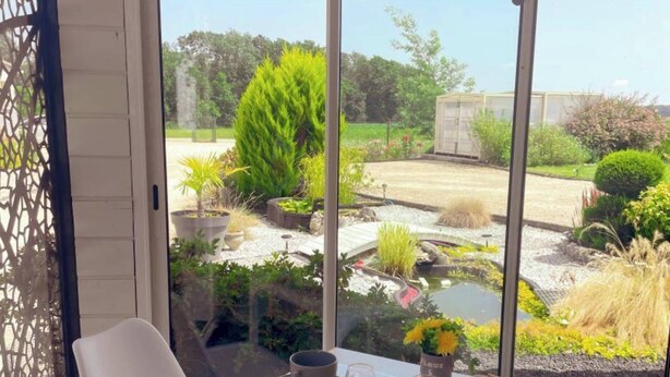 Una mesa de comedor con alimentos para el desayuno y vista a un jardín por un ventanal.