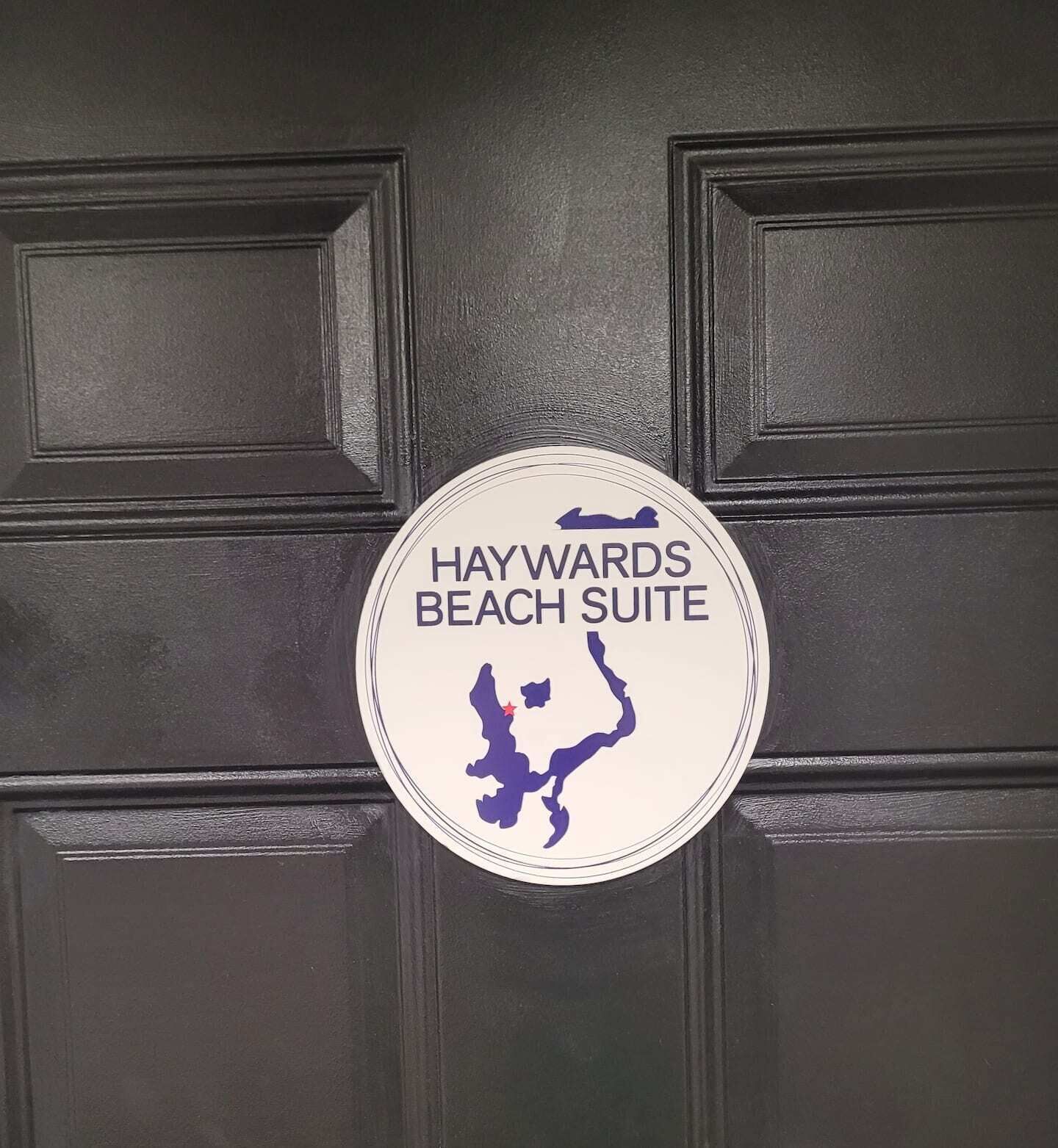 En skylt på en dörr som anger namnet på ett hotell eller en bostad, till exempel "Haywards Beach Suite".