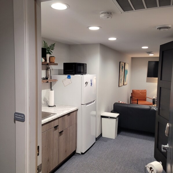A compact kitchen with a microwave, refrigerator, and a small trash bin.