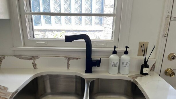 A kitchen with two stainless steel sinks, a window with a view of buildings, and two bottles labeled 'HANDS' and 'DISHES'. - This house is a 2 bedroom(s), 1 bathrooms, located in Nashville, TN. (Nashville)