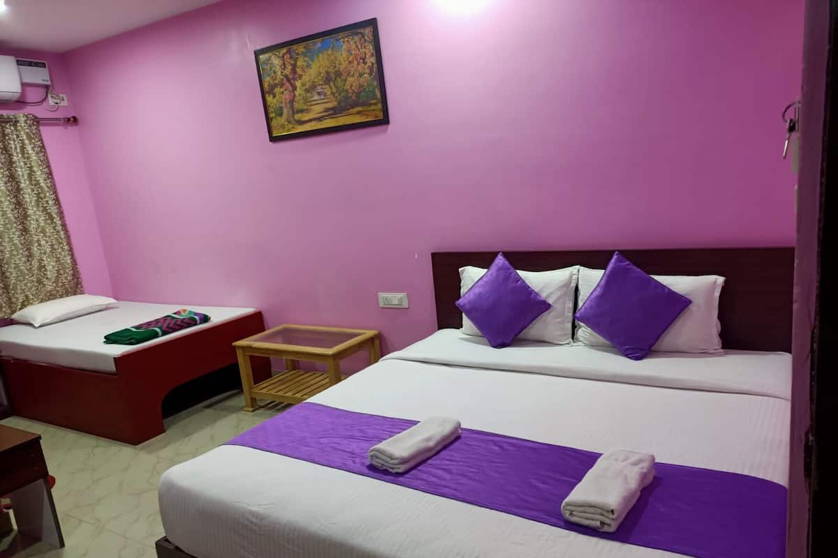 A hotel room with two beds, a small table, a painting on the wall, and a window with curtains.