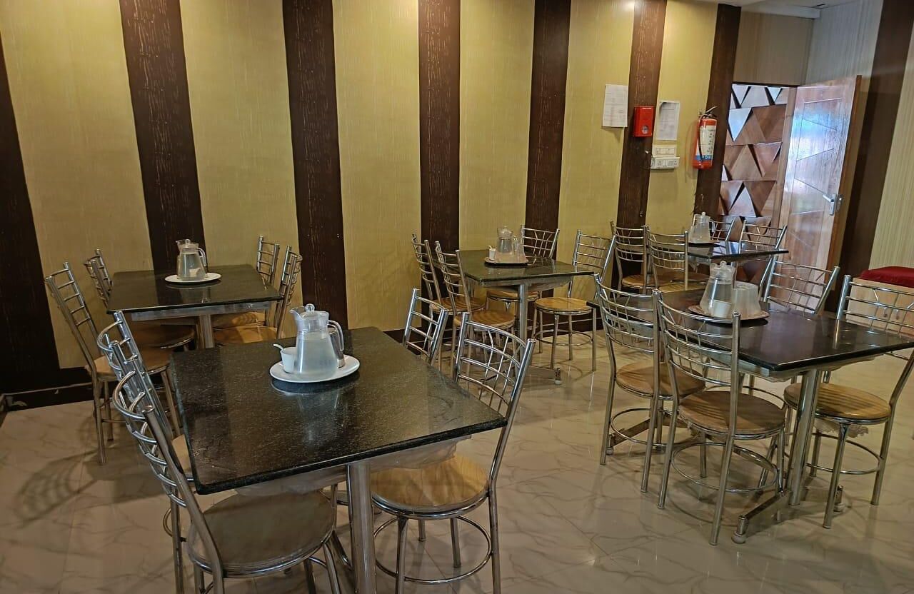 A dining area with multiple tables and chairs, some with metal frames and others with wooden seats.