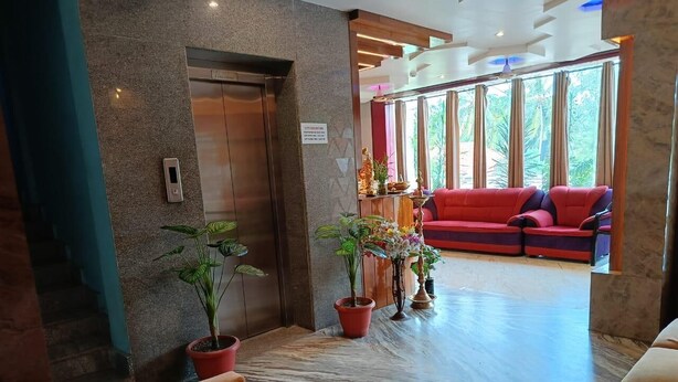 A lobby with a marble floor, red seating area, and potted plants. - Hotel AMR GRAND (Port Blair)