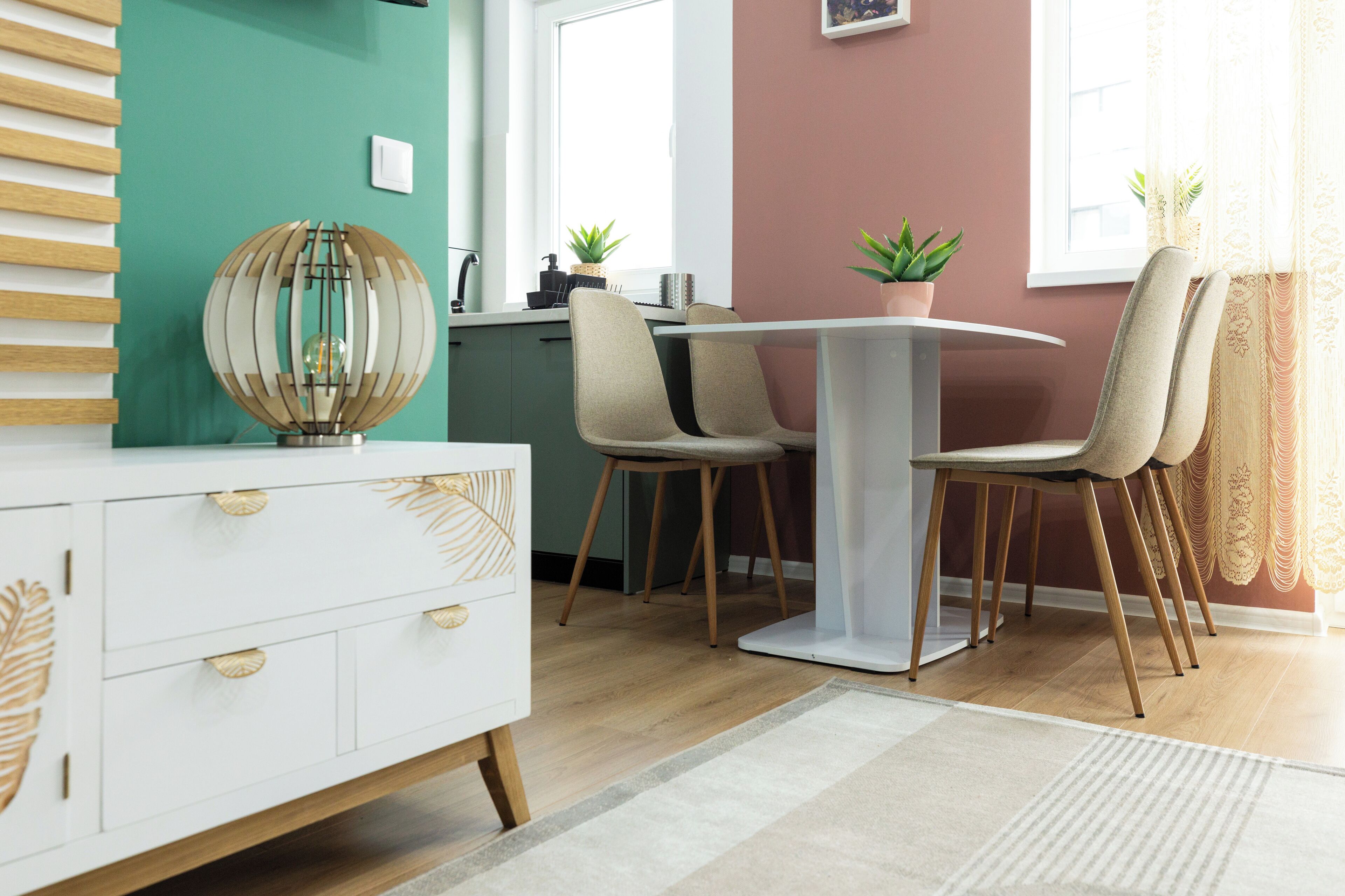Un comedor moderno con una mesa blanca, sillas color beige y una mesa redonda con cubierta de vidrio.