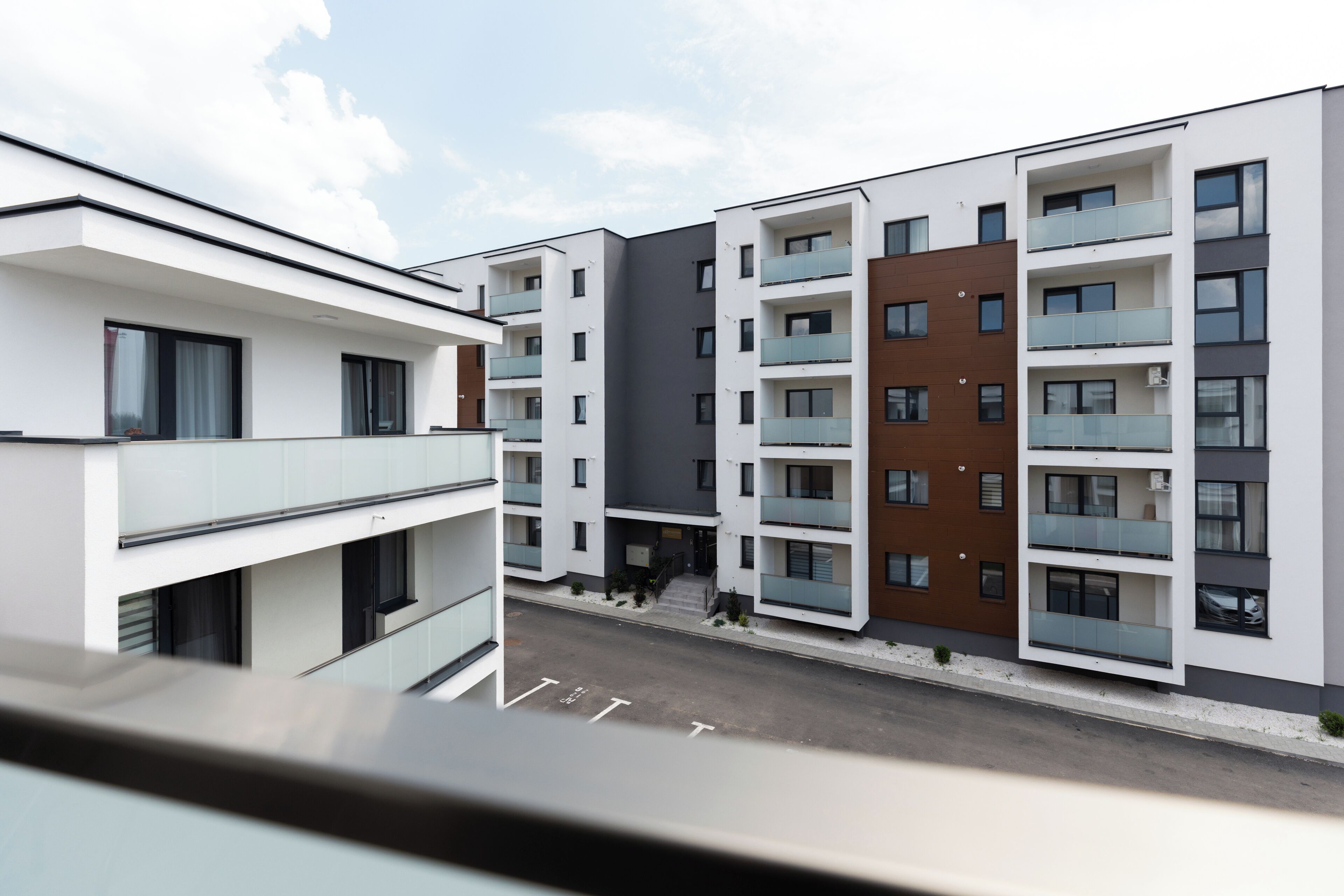 Un edificio residencial moderno de varios pisos con balcones y cielo despejado.