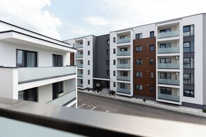 A modern multi-story residential building with balconies and a clear sky. - Blooming Studio (Baia Mare)