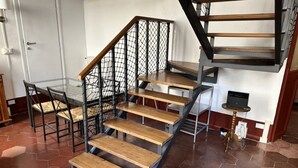 Eine Treppe mit Holzdielen und Metallgeländern, die zu einer Empfangshalle mit einem Glastisch und Stühlen führt.