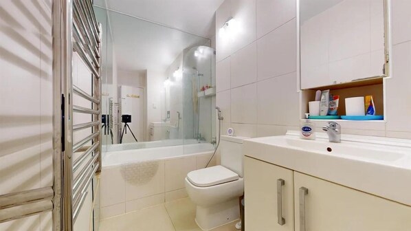 A modern bathroom with a glass-enclosed shower, a white toilet, and a vanity with a mirror. - London Chic Apartment Retreat (London)