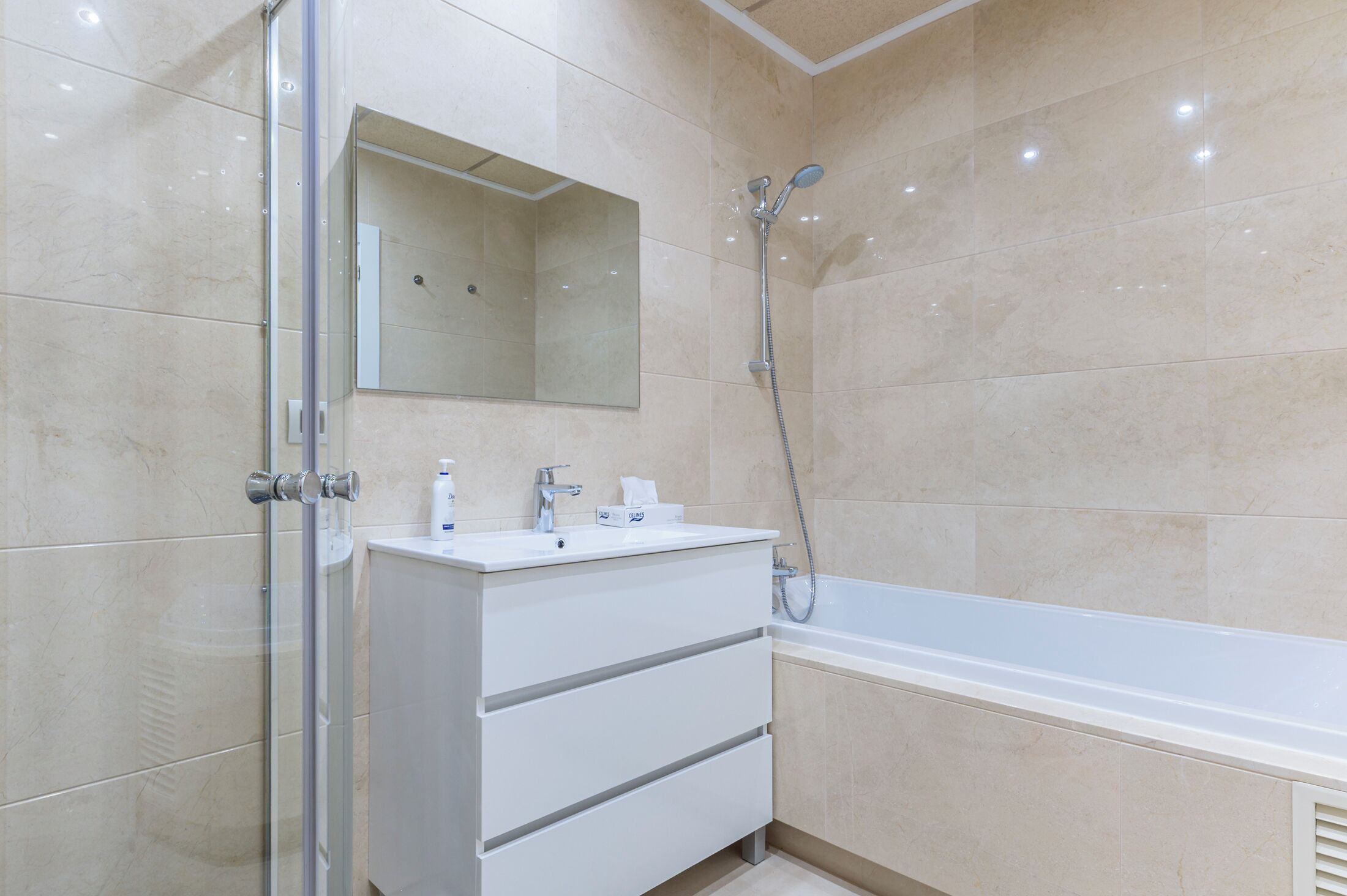 A modern bathroom with a glass shower enclosure, a white vanity with a mirror, and a bathtub.