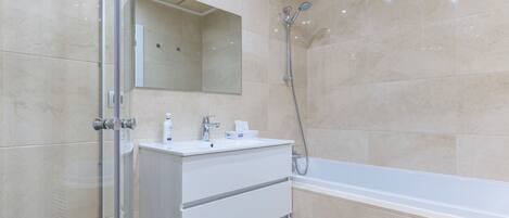 A modern bathroom with a glass shower enclosure, a white vanity with a mirror, and a bathtub.