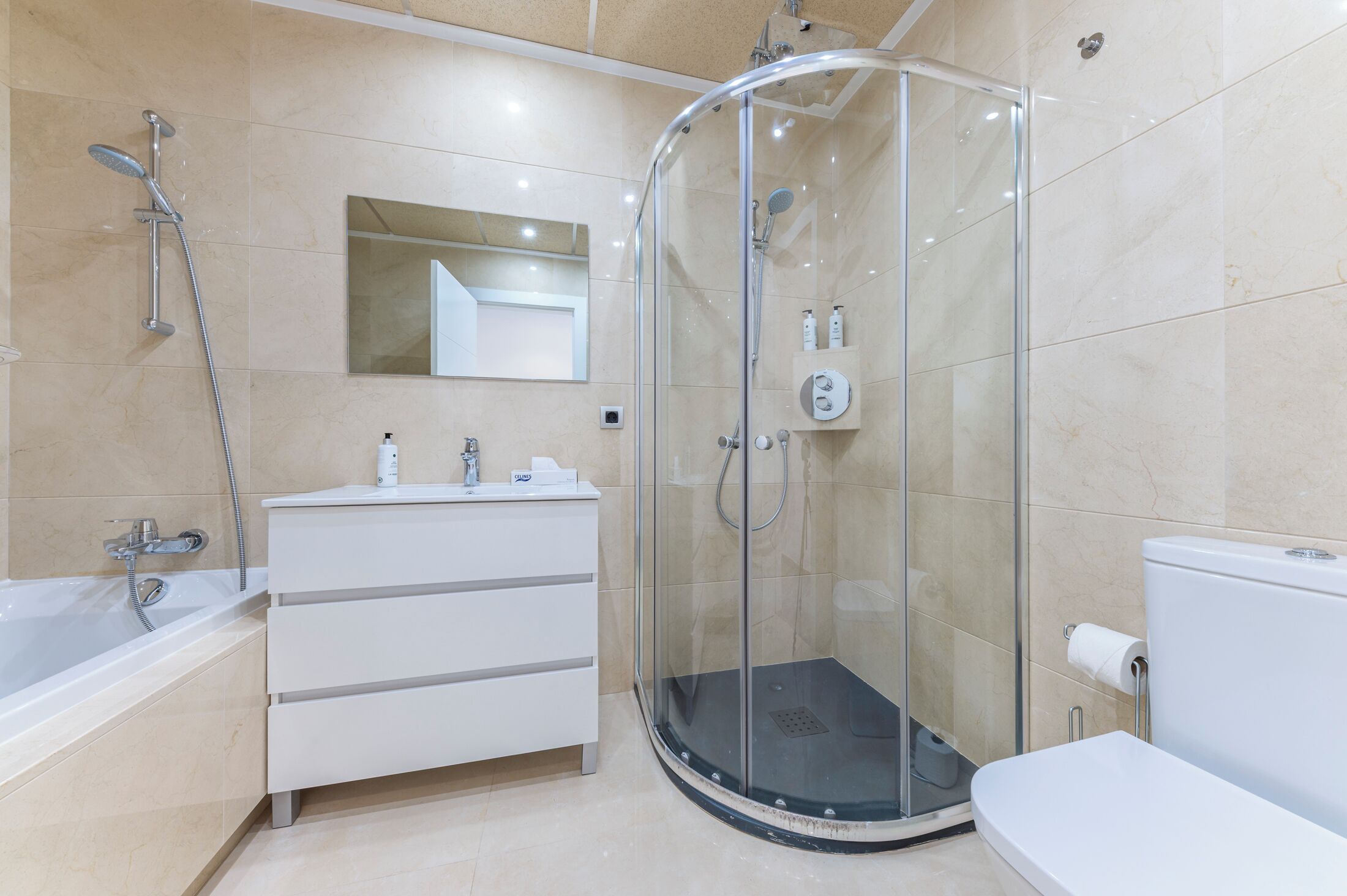 Un bagno moderno con doccia vetrata, un mobile lavabo bianco con specchio e il water.