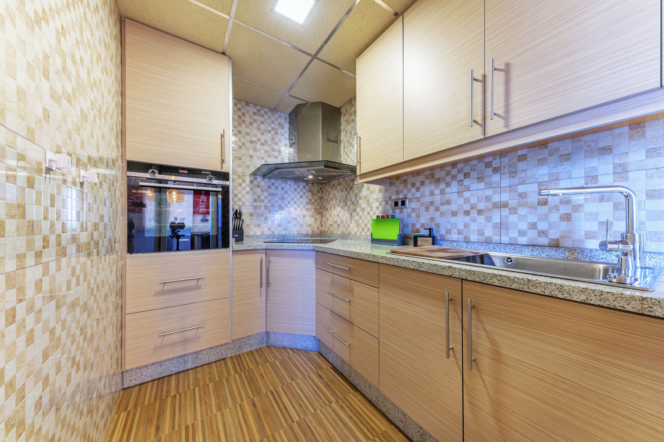 Een moderne keuken met houten kastjes, een roestvrijstalen spoelbak en een inbouwoven.