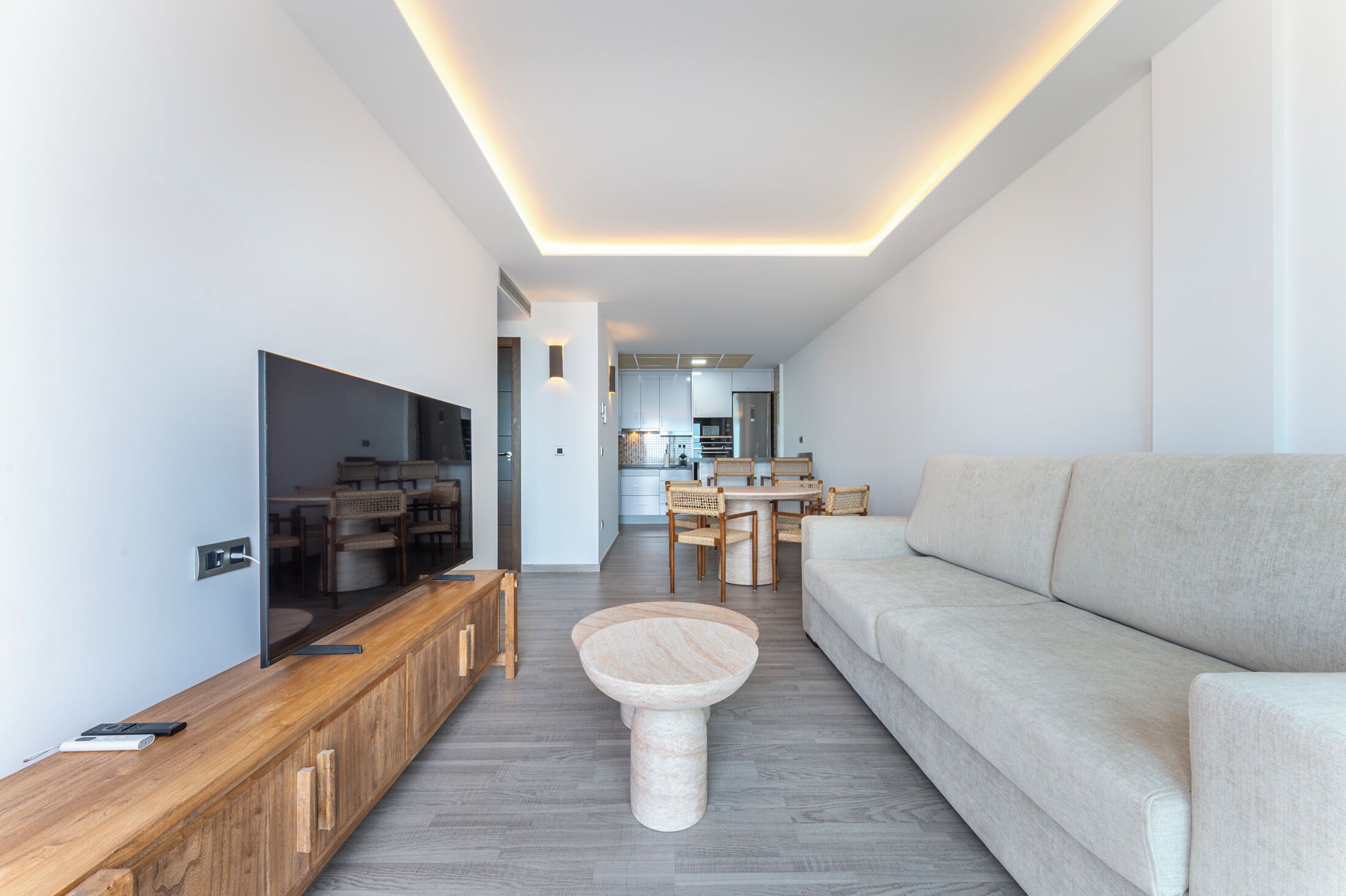 A modern living room with a flat-screen TV, wooden entertainment unit, and a round coffee table.