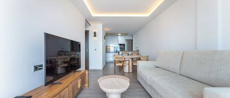 A modern living room with a flat-screen TV, wooden entertainment unit, and a round coffee table.