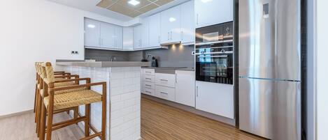 Eine moderne Küche mit weißen Schränken, einem Edelstahlkühlschrank und Holzboden.