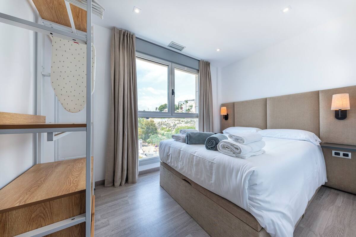 Une chambre d’hôtel moderne, équipée d’un lit, d’un bureau et d’une fenêtre avec des rideaux.