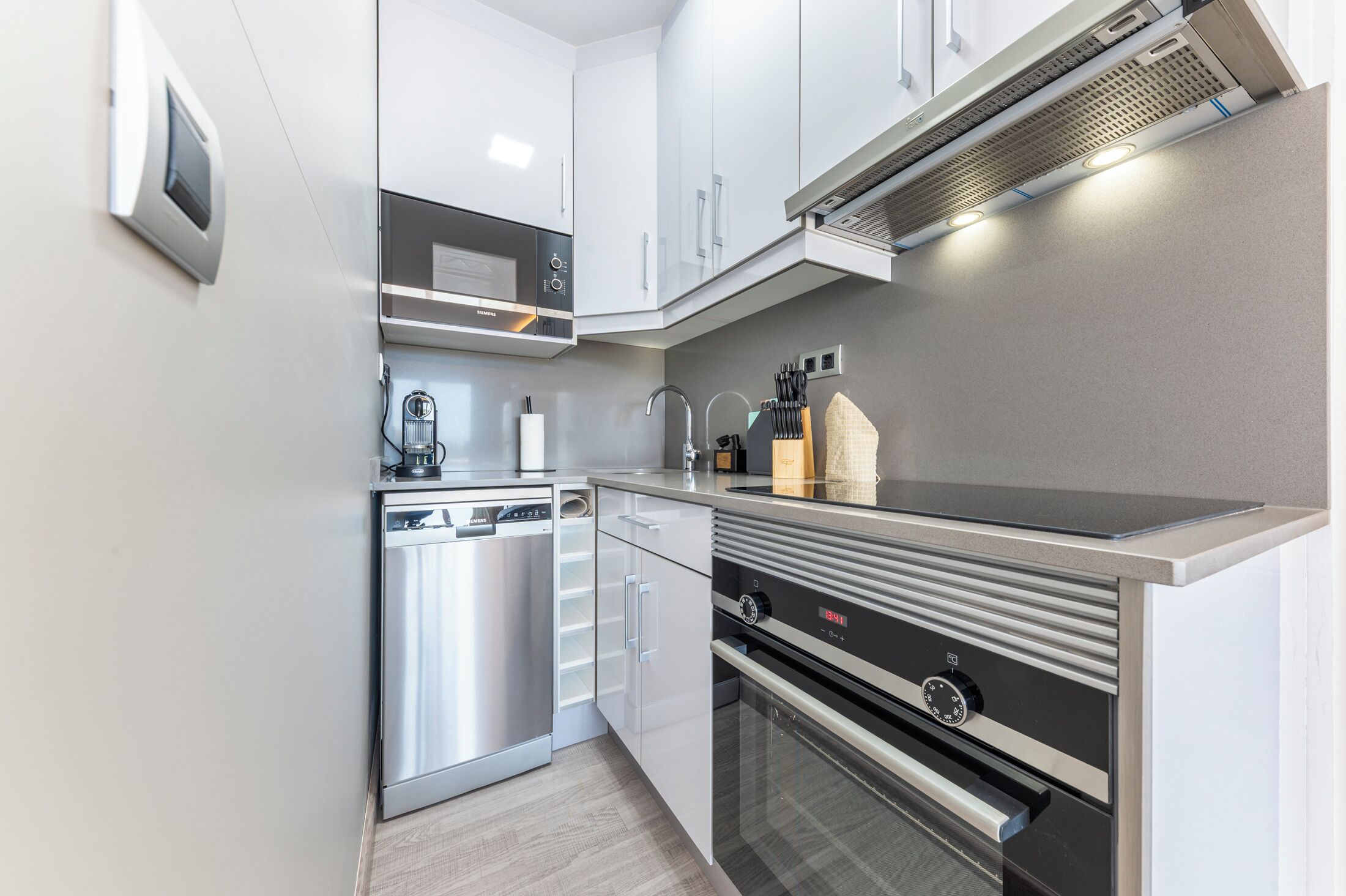 A modern kitchen with stainless steel appliances, white cabinetry, and a built-in oven.