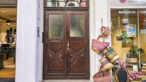 A building with a double wooden door, a small balcony with a clock, and a shop window displaying bags and a chair. - Holiday apartment in the heart of the old town (Heidelberg)