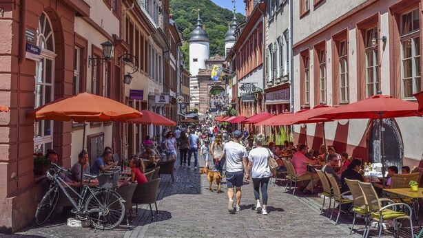 A cobblestone street lined with outdoor seating areas and bicycles. - Holiday apartment in the heart of the old town (Heidelberg)