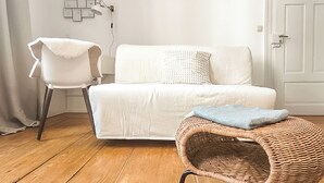 A room with a white sofa, a wicker chair, a white armchair, and a wooden floor. - Holiday apartment in the heart of the old town (Heidelberg)