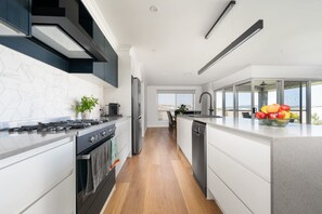A modern kitchen with a central island, built-in appliances, and a view to the outside.