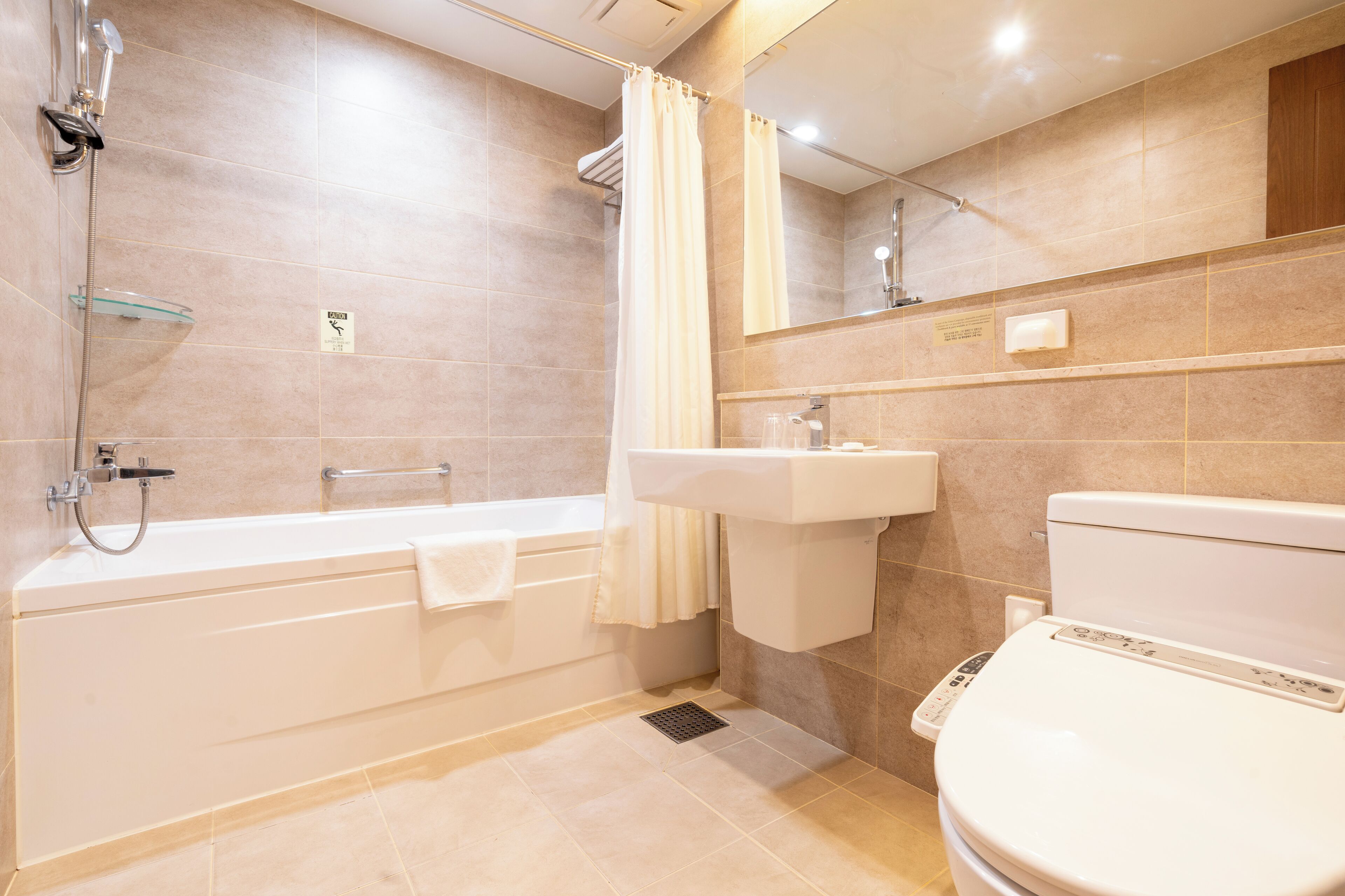 A modern bathroom with a bathtub, shower, sink, and toilet.