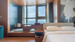 A modern hotel room with a large window, a bed, a desk, and a seating area. - hotellamouette (Busan)