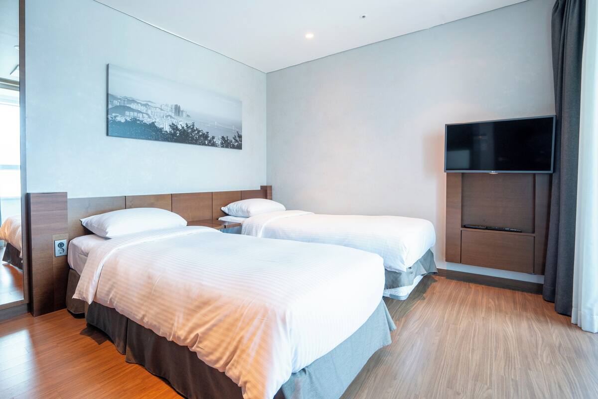 Habitación de hotel con dos camas, un televisor de pantalla plana y un cuadro en la pared.