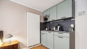 A compact kitchen with light blue cabinets, a microwave, and a small countertop with kitchen essentials. - Limehome Kassel Wilhelmsstraße (Kassel)