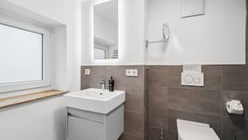 Une salle de bain moderne avec un lavabo blanc, un miroir et des toilettes.