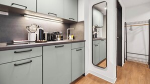 A modern kitchen with grey cabinets, a countertop with various appliances, and a large mirror. - Limehome Kassel Wilhelmsstraße (Kassel)