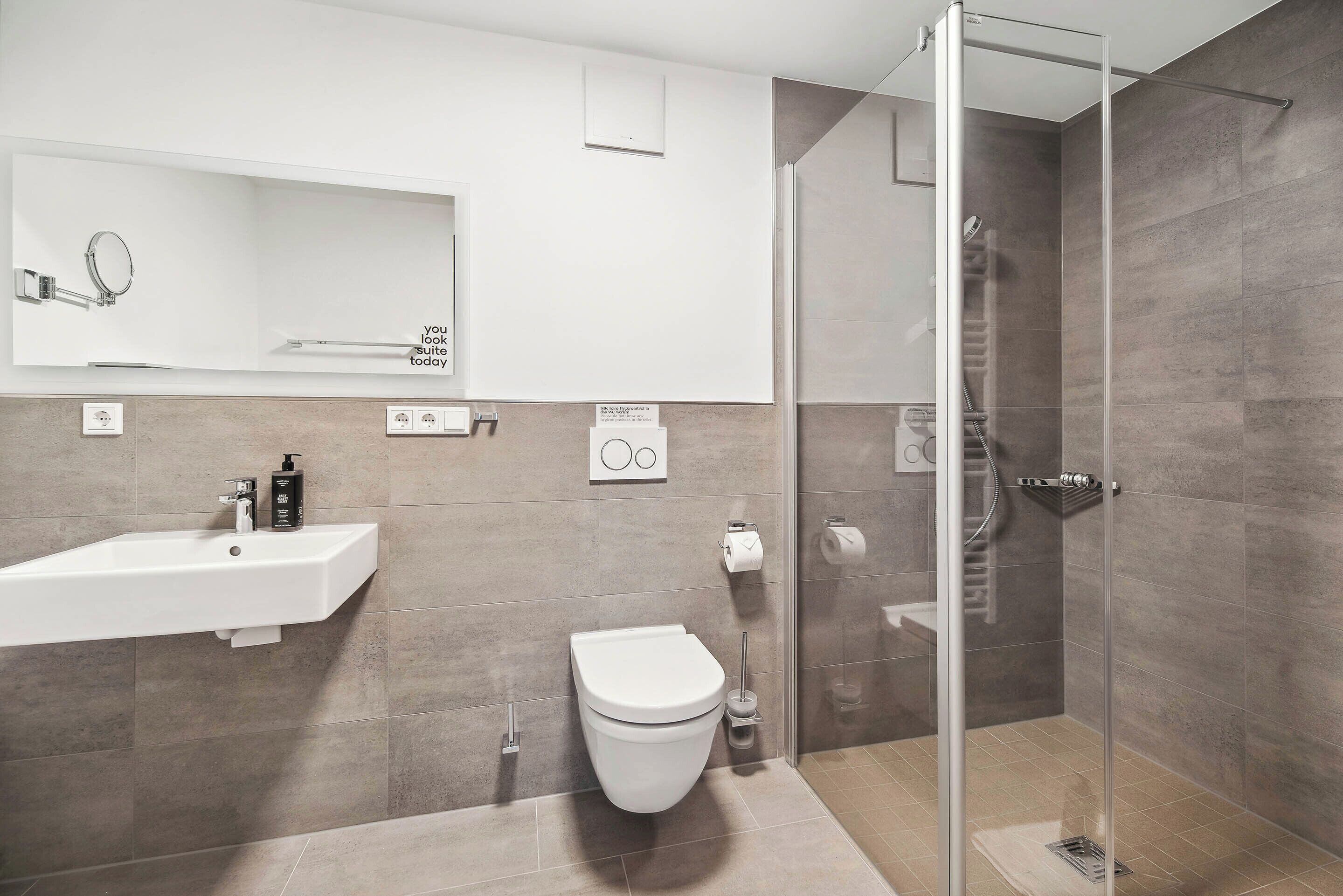 Un bagno moderno con doccia vetrata, lavandino bianco e water.
