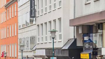 Una vista di strada con edifici, un cartello con il marchio Limehome e passanti.