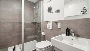 A modern bathroom with a glass shower enclosure, a white sink, and a toilet.
