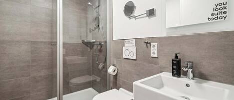 Ein modernes Badezimmer mit Duschkabine aus Glas, einem weißen Waschbecken und einer Toilette.