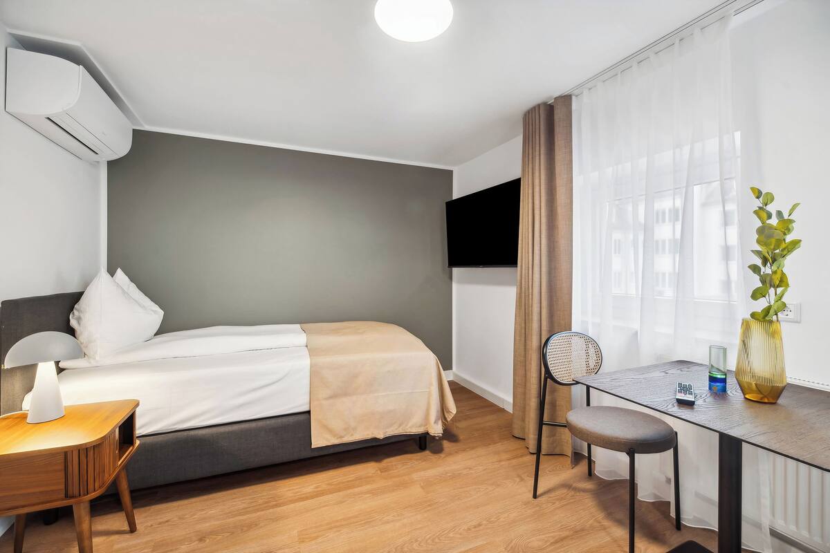 Une chambre moderne avec un lit, une table de chevet et un bureau avec une chaise.